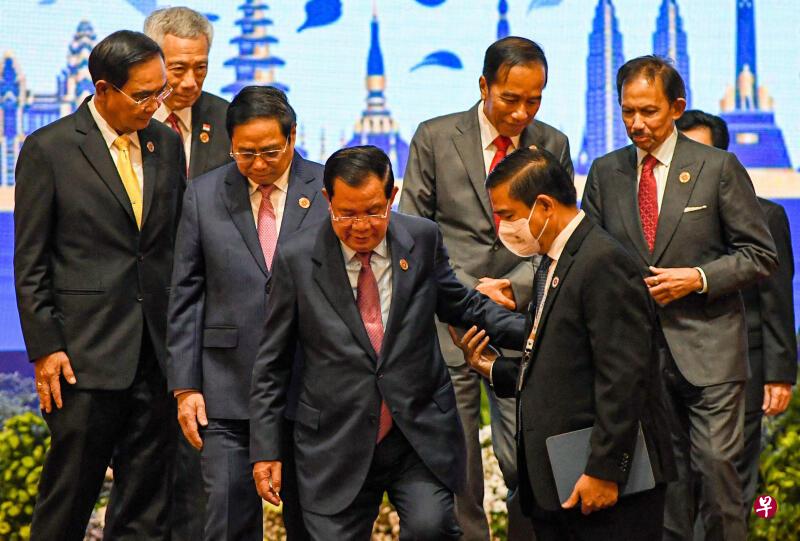 佩戴口罩的现场工作人员搀扶着柬埔寨首相洪森走下舞台