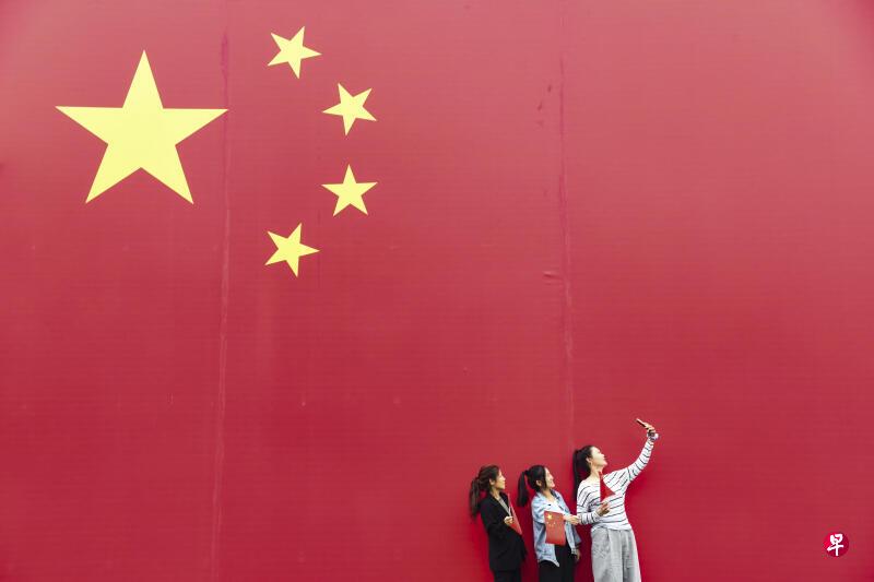 10月1日，在中国河南省济源市那些年小镇，游客与中国国旗合影